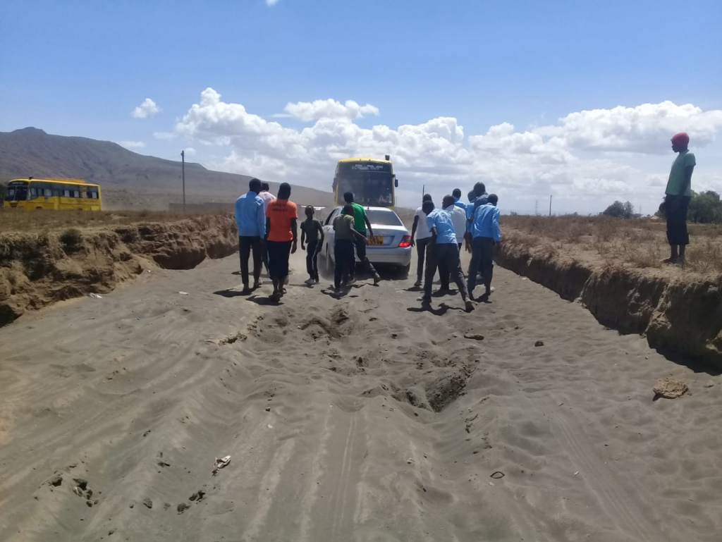 Students pushing aside a vehicle stuck in the sand